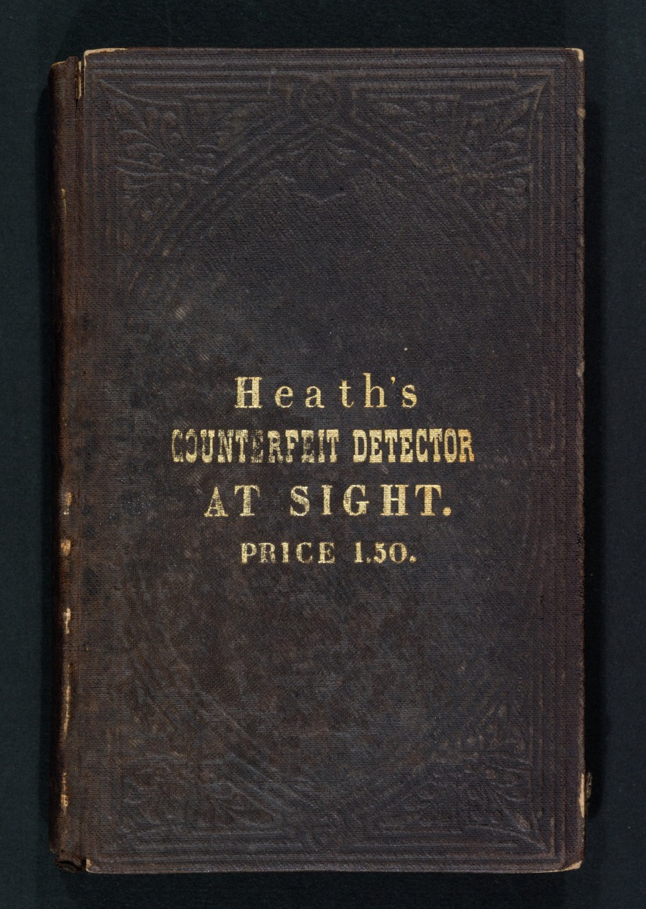 Cover of an old book titled Heaths Counterfeit Detector At Sight, priced at $1.50. The cover is dark with embossed decorative patterns.