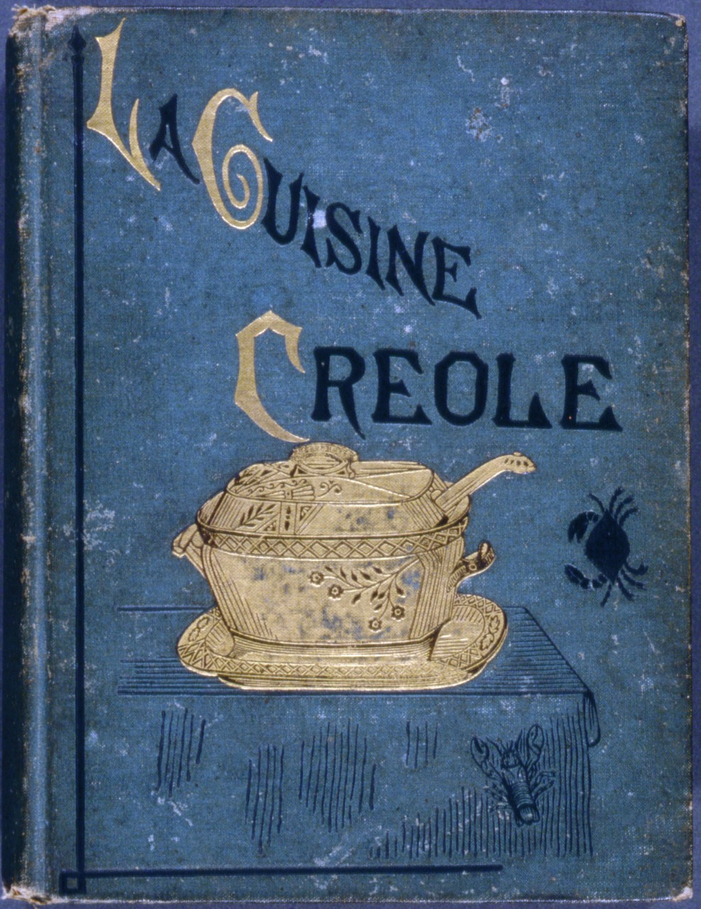 A vintage book cover for La Cuisine Creole in blue, featuring a golden illustration of a lidded serving dish with a ladle. The title is in stylized text, and a small crab illustration is on the right side.