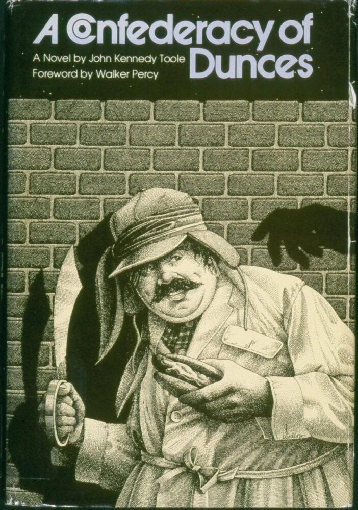 A book cover for A Confederacy of Dunces featuring a man with a mustache and hat holding a hot dog. He is standing against a brick wall, and a shadowed hand reaches towards him from the background.