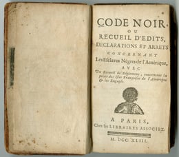 An open old book titled Code Noir, discussing laws regarding enslaved people in the Americas. The page displays a title, publication details in French, and a small illustration of a person at the bottom.