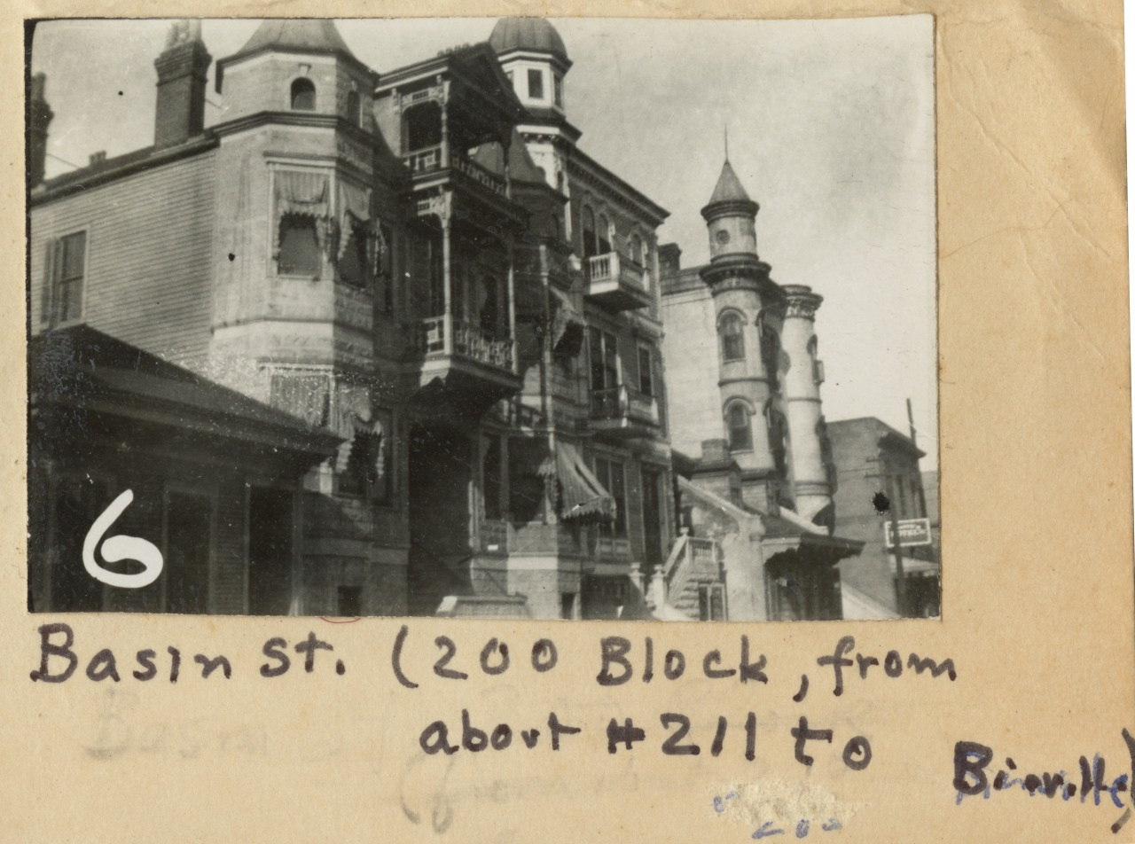 Black and white photograph of historic buildings on Basin Street, with intricate architectural details, balconies, and a round tower. Handwritten text below reads: Basin St. (200 Block) from about #211 to Bienville.