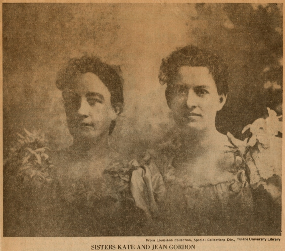 Sepia-toned vintage photograph of two women in ornate dresses with floral details. They stand closely together, looking directly at the camera, surrounded by faint, textured background.