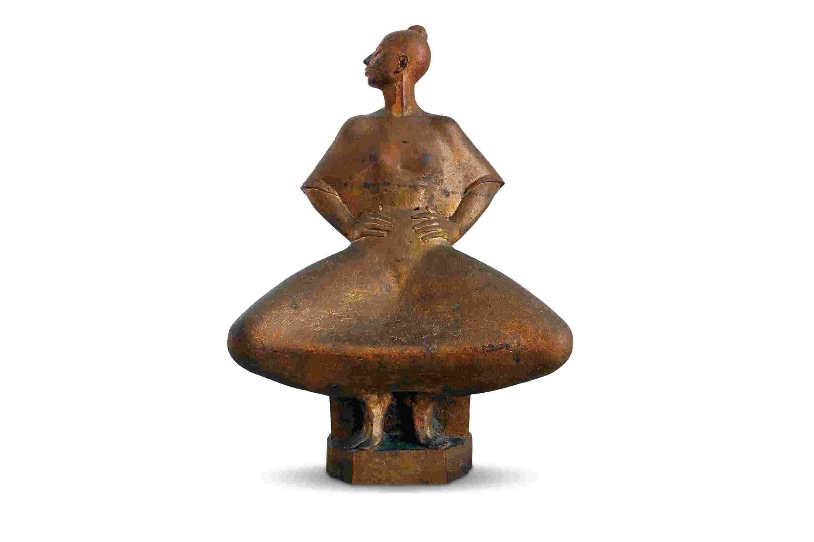 Bronze sculpture of a figure with a broad, conical lower body and elongated torso. The figures arms rest on its hips, and the head is turned to the side. The artwork features smooth, rounded contours and sits on a pedestal.