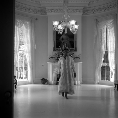 A black and white photo shows artist Carrie Mae Weems dancing inside Nottoway Mansion.