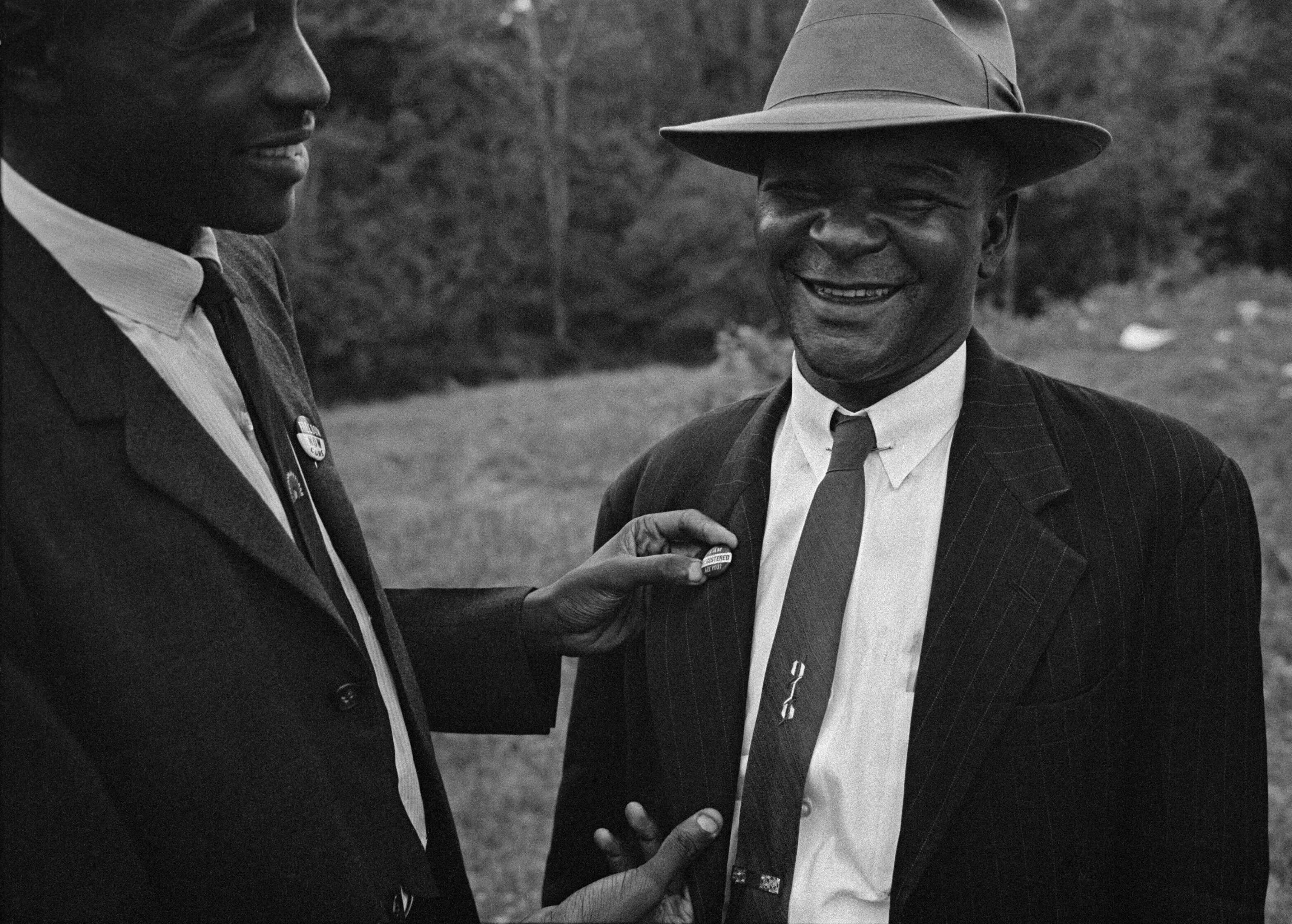 CORE organizer Ronnie Malcolm Moore pins Rev. Joseph Carter with a voter registration button in St. Francisville, 1963.