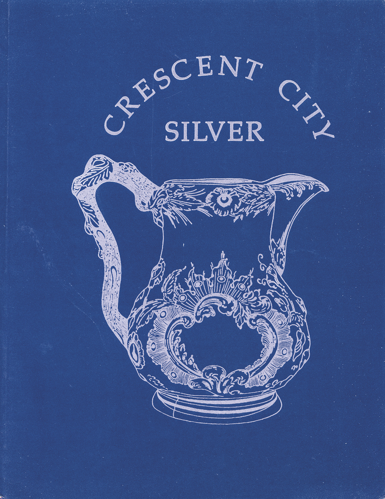 Blue background with a white illustration of an ornate silver pitcher. The text at the top reads Crescent City Silver. The pitcher features intricate floral and filigree designs.
