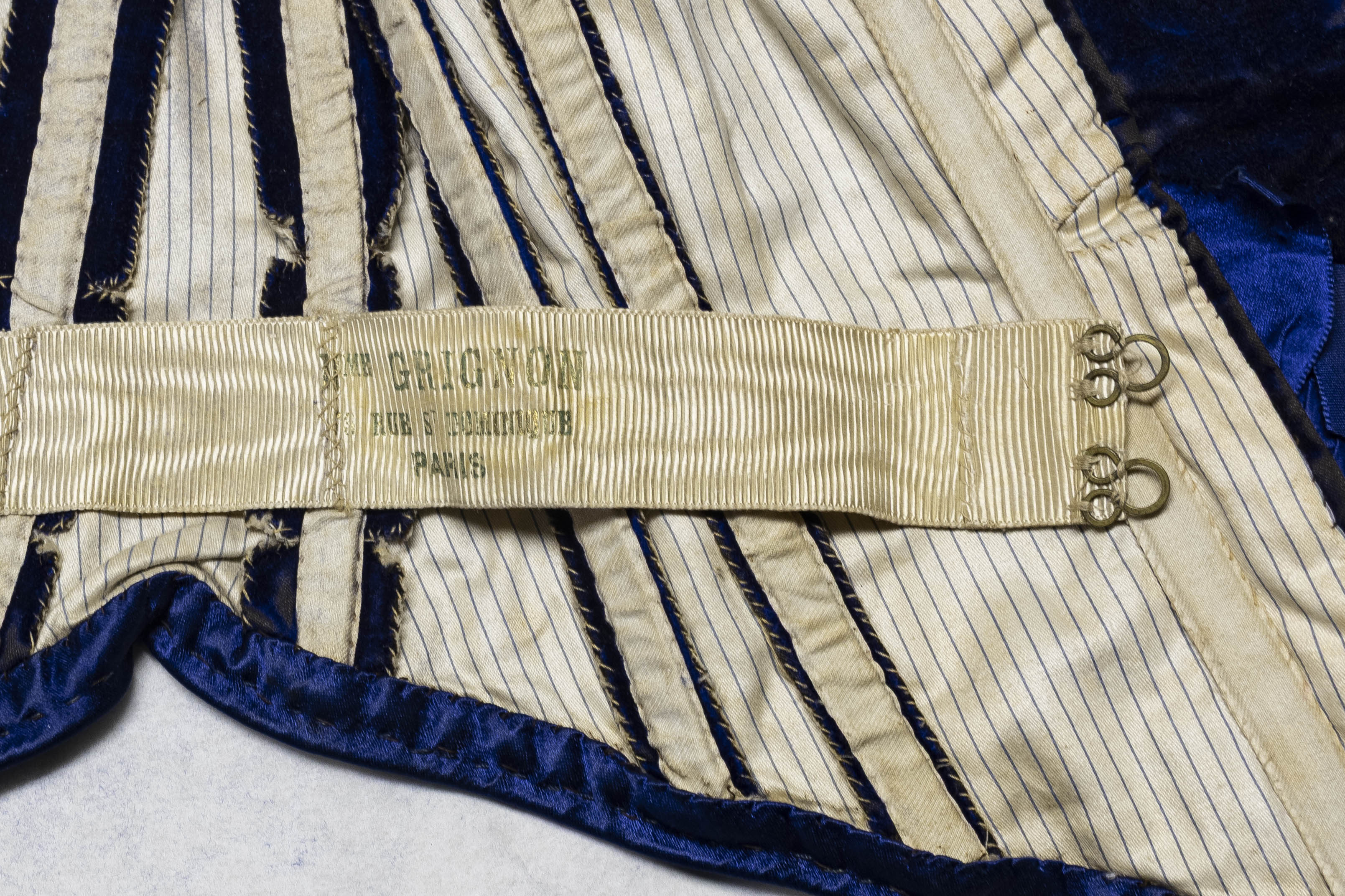 View of the bodice interior showing striped lining and waistband with hook-and-eye closures, with a tag labeled "GRIGNON".