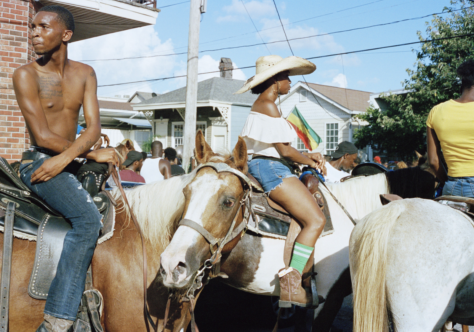 Several men and women ride horses at a second line parade.
