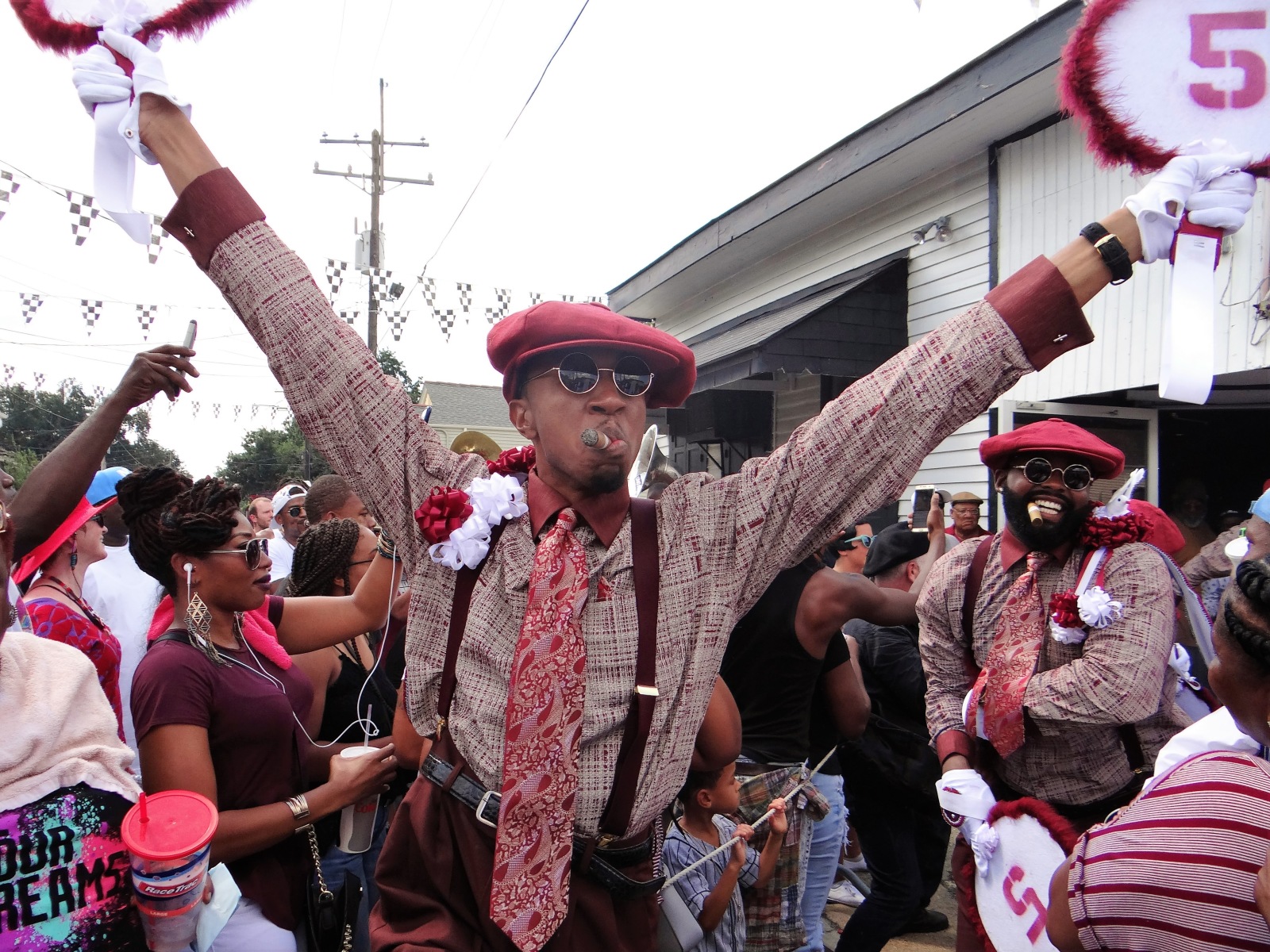 Brand Williams, wearing a plaid shirt, pink patterned tie, suspenders, and a beret comes out of the door before a YMO, Jr. parade in 2016.