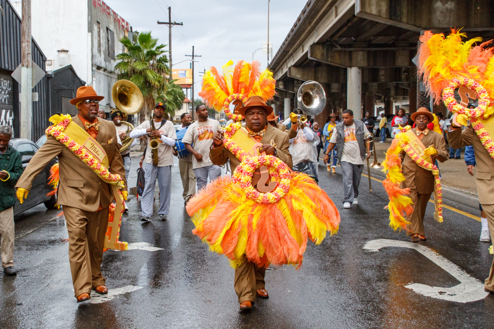 Michael Redditt, Troy Materre, and Corey Woods of ? Mark Social and Pleasure Club at a Dumaine Gang parade in 2016. The Claiborne overpass can be seen behind them.