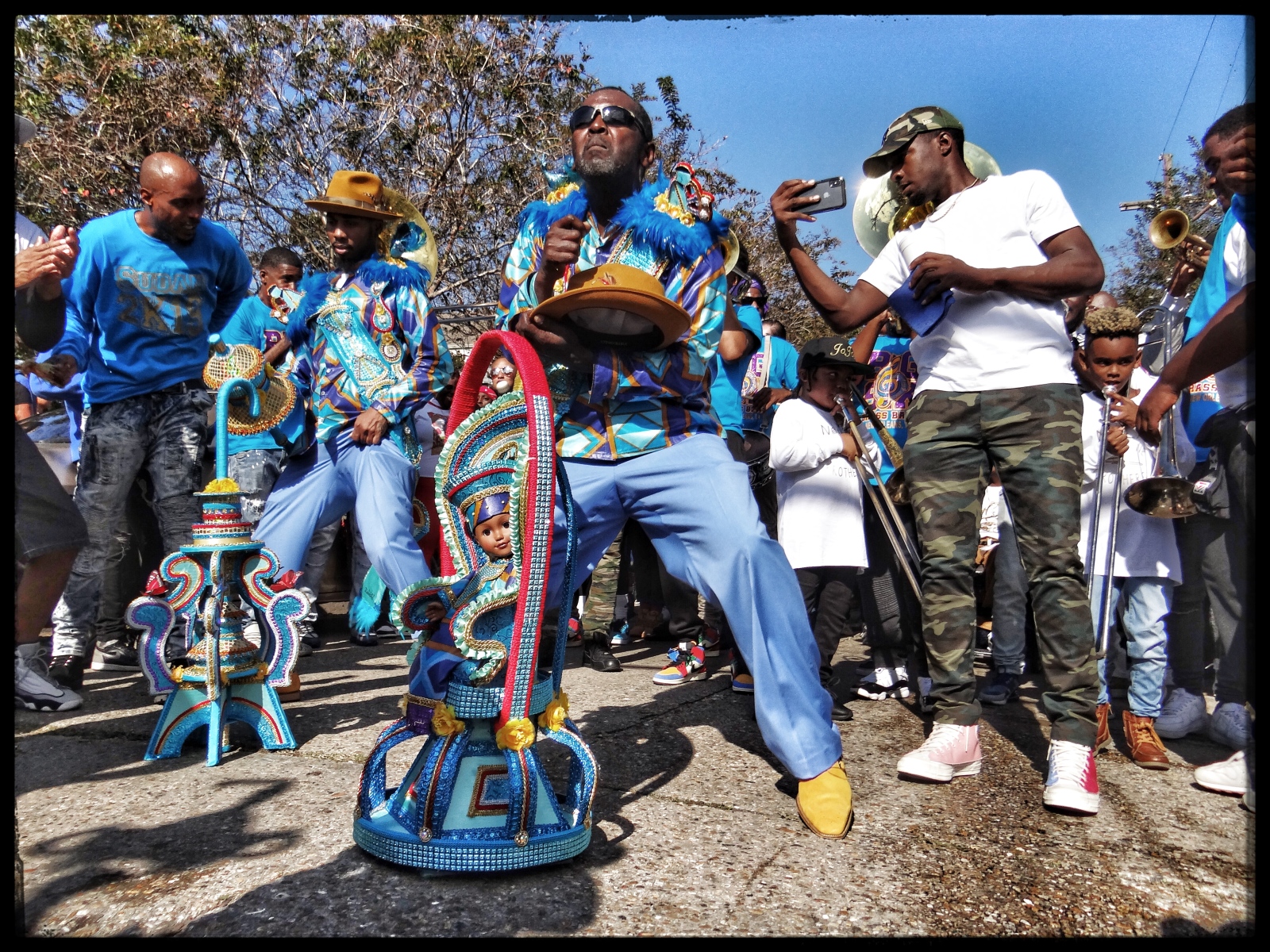 Adrian "Coach Teedy" Gaddies and Keith Radcliffe dance during a Sudan second line parade, flanked on onlookers on either side of the street.