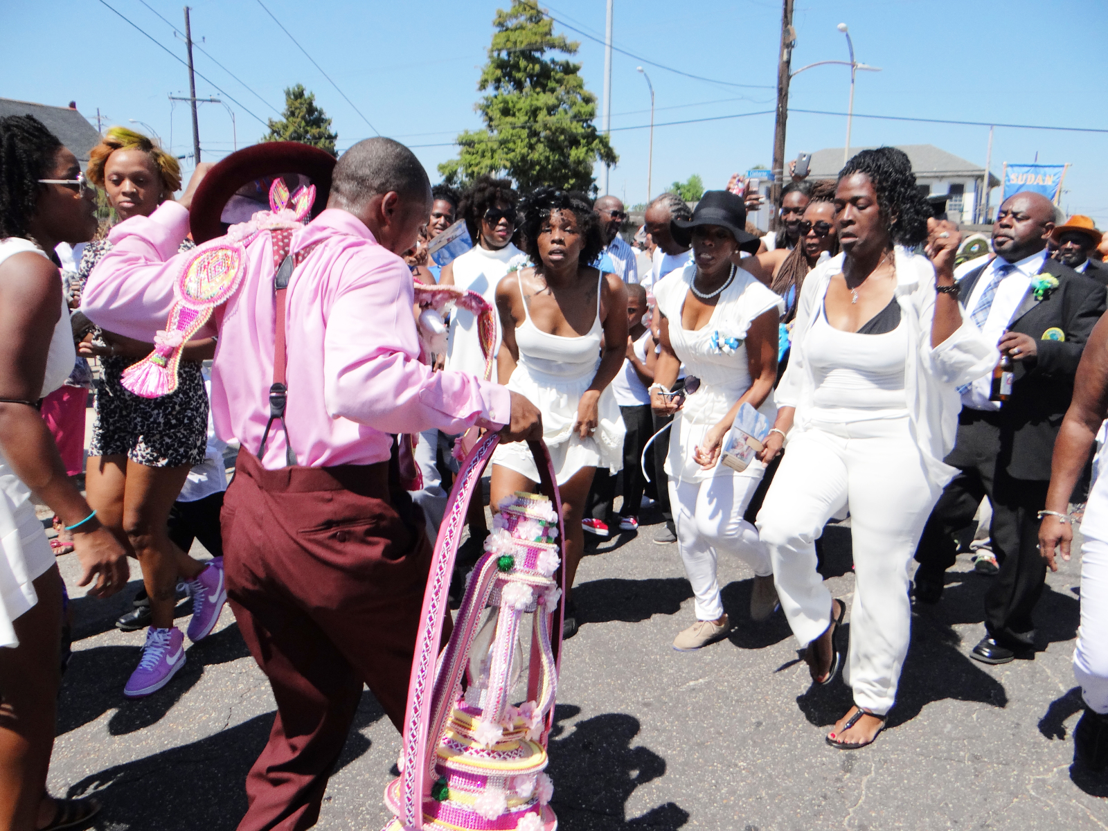 Cheryl Ann Roberts, Nikisha Grinstead, and Shelia Ross dance at Kenneth Dykes' funeral second line parade. They are wearing matching white outfits.
