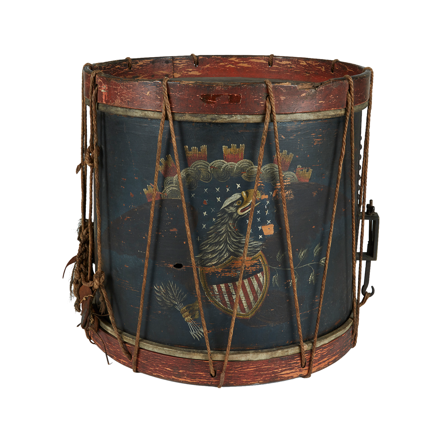 A vintage military drum with a worn, red wooden frame and rope tensioning. The drum features a painted design of an eagle clutching an American shield amidst stars and clouds. The paint is faded, giving it an antique appearance.