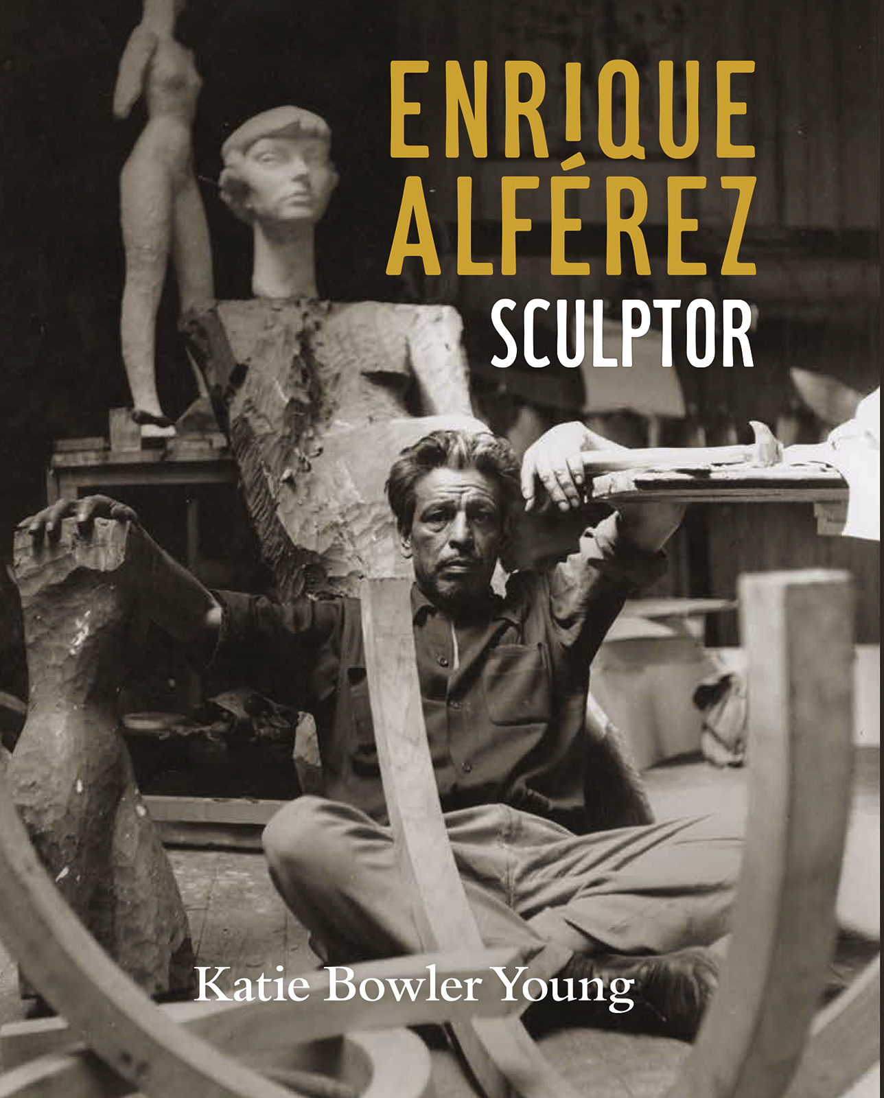 Black and white cover image of Enrique Alférez: Sculptor by Katie Bowler Young. Features a man seated among sculptures and sculpting tools, with Enrique Alférez Sculptor text in bold yellow and white.