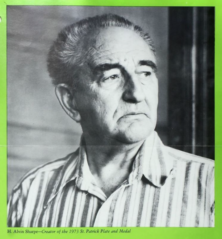 Black and white photo of an older man with short hair, wearing a striped shirt. He is looking to the side. The border is green, and theres text mentioning him as a creator of a 1973 St. Patrick plate and medal.