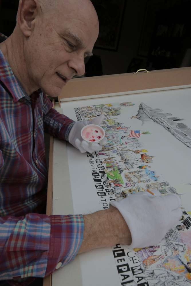 An artist wearing white gloves is sitting at a table, painting a detailed illustration depicting a bustling scene with various people, flags, and text. The artist appears focused on adding colorful details to the artwork.