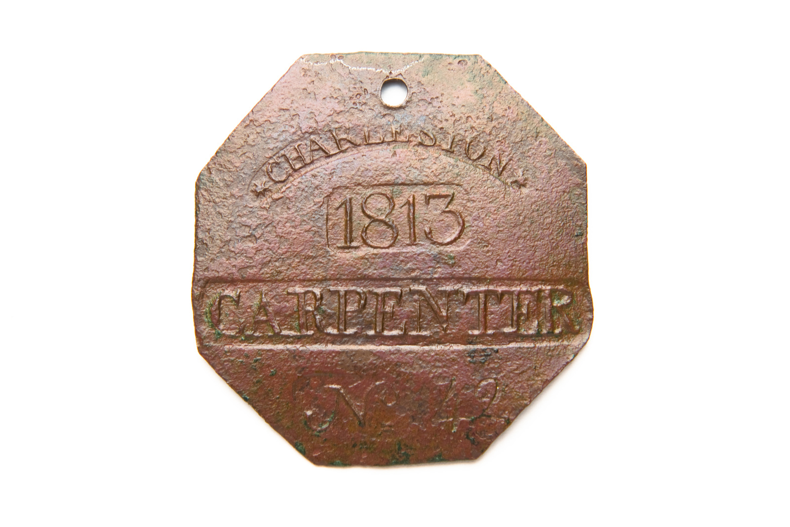 A slave badge made in 1813 says "carpenter" in block lettering.