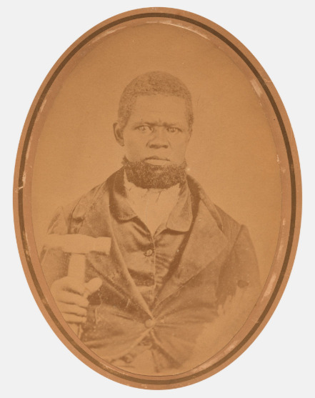 Photograph of an unidentified Black craftsperson with a hammer