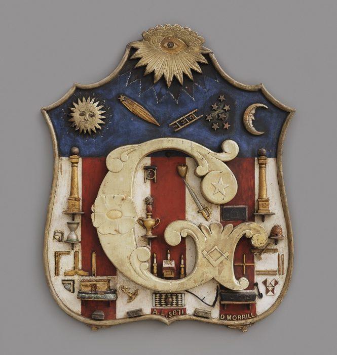 A decorative emblem features a stylized letter G at its center. Surrounding it are various objects, including tools, a sun, a moon, and stars. The background consists of red, white, and blue sections with ornate details.