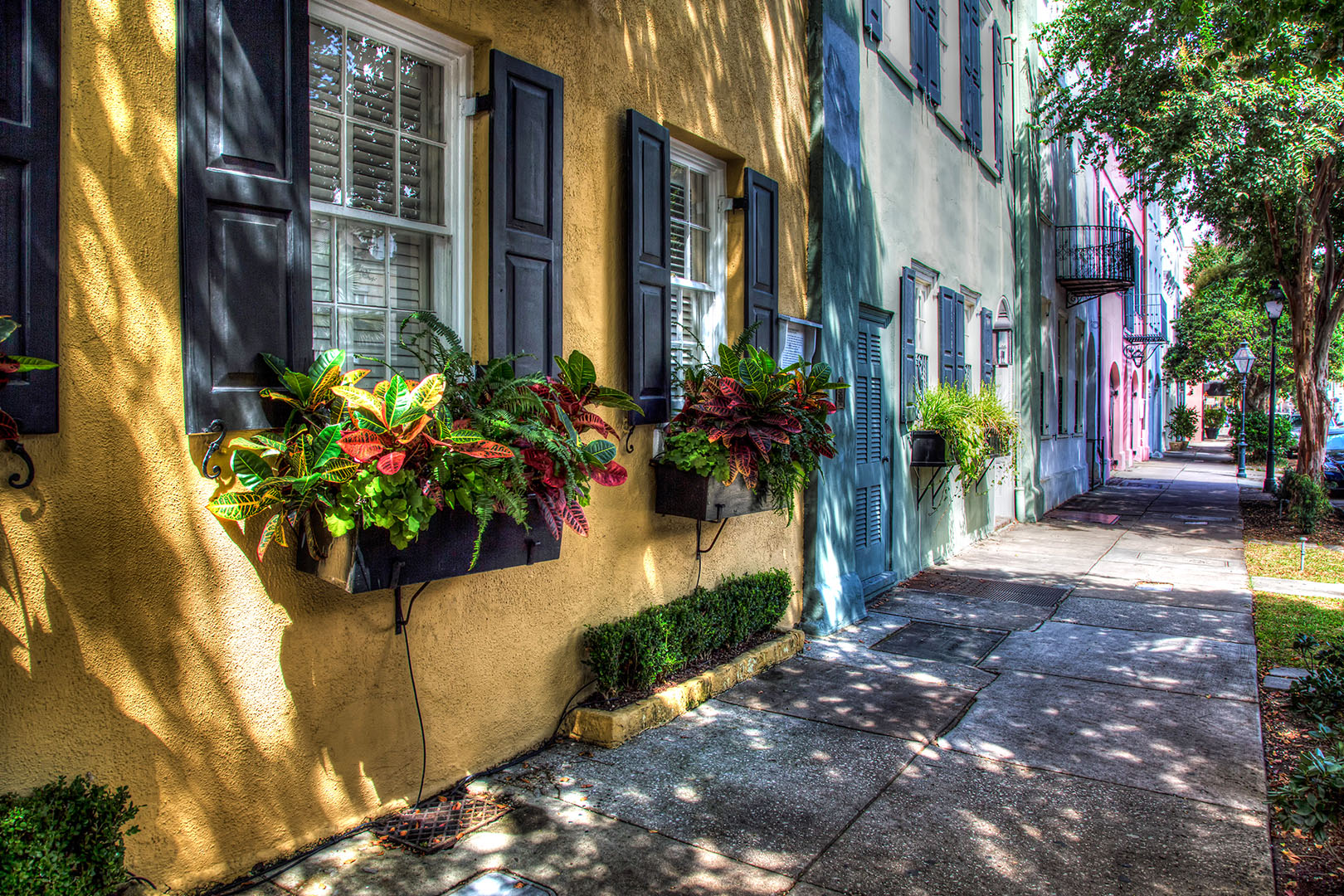 A view of a yellow stucco home that is part of Rainbow Row in downtown Charleston.