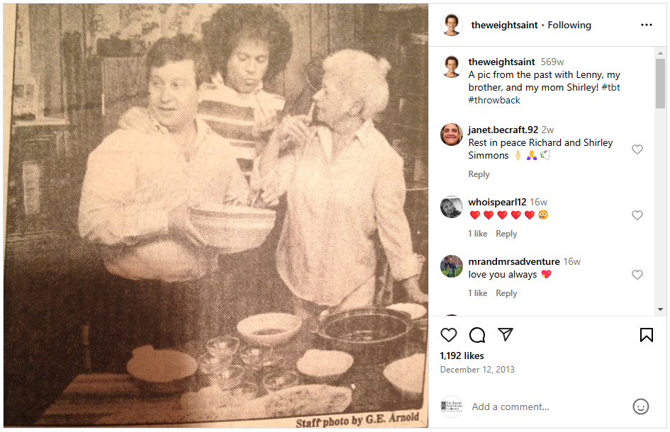 A vintage black and white photo shows three people in a kitchen: two men and a woman. One man holds a jar, the woman smiles, and the other man looks on. Various kitchenware and food items are on the table.