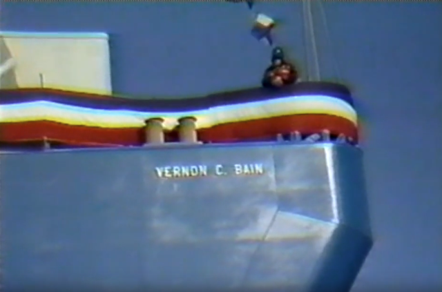 A screenshot from a vintage color film shows part of a ship with the name "VERNON C. BAIN" written on the side.
