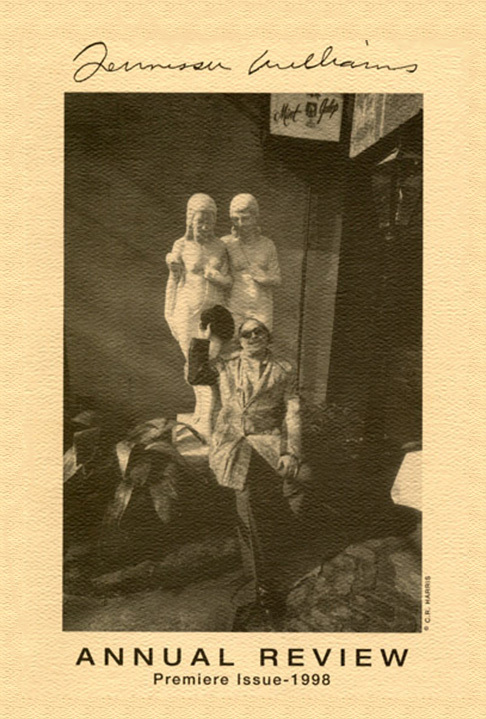 Sepia-toned cover of the Annual Review Premiere Issue - 1998 features a person sitting in front of a sculpture of two figures. Theres a signature at the top and the image has a textured background.