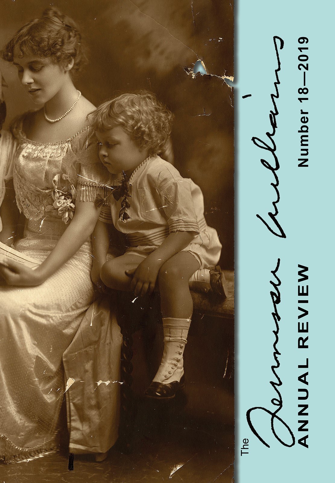 A vintage photograph of a woman and a child sitting together. The woman is in a long dress, reading, while the child sits on the edge of a table. The image is part of a publication labeled Annual Review Number 18 – 2019 by someone named Williams.