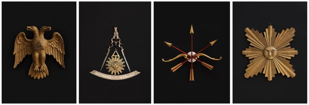 Four images of ceremonial symbols on a black background: a double-headed eagle, a compass with rays, a set of arrows with ribbons, and a sunburst with a face. Each piece is detailed and ornate, suggesting historical or symbolic significance.
