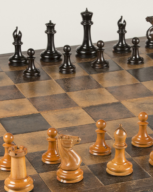 A chess board with a checkered pattern is set up for play. The brown pieces, including a rook, knight, and bishop, are positioned in the foreground, while black pieces are lined up in the background.