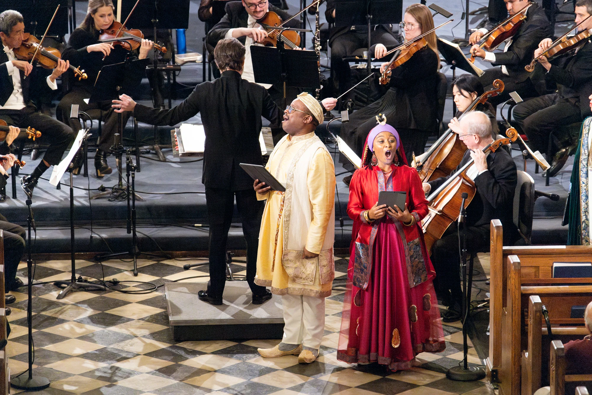 Two opera singers in costume sing in front of the Louisiana Philharmonic Orchestra in St. Louis Cathedral.