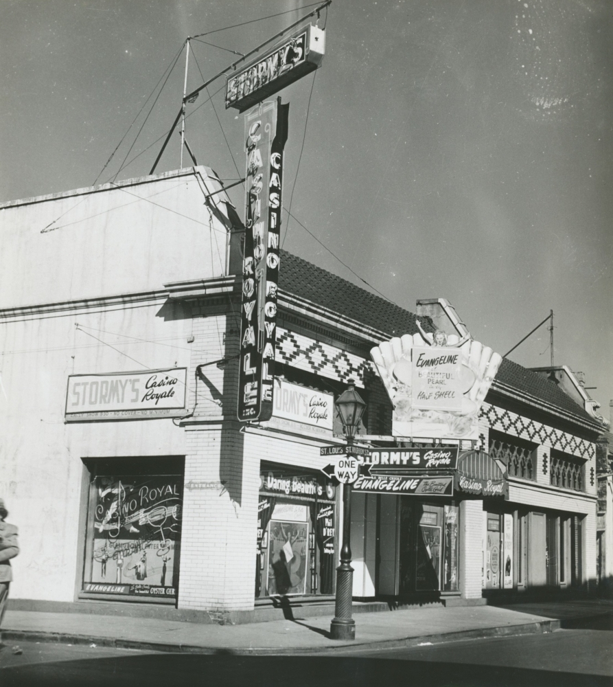 A vintage photograph of Stormys Casino Royale on a street corner. The building features neon signs and a marquee advertisement for a show, Evangeline. The facade has classic architecture and decorative elements, with clear sky in the background.