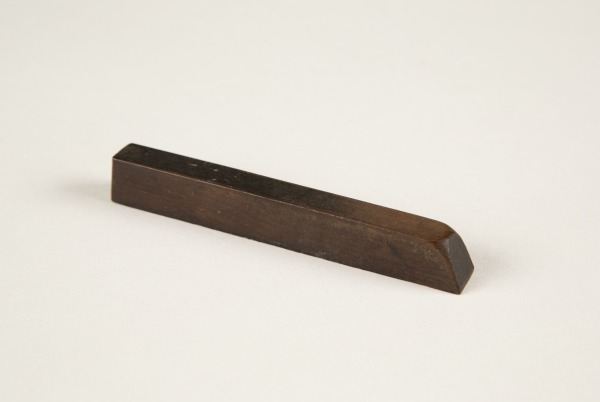 A dark brown, rectangular bar with a slightly slanted end, placed on a plain white background.
