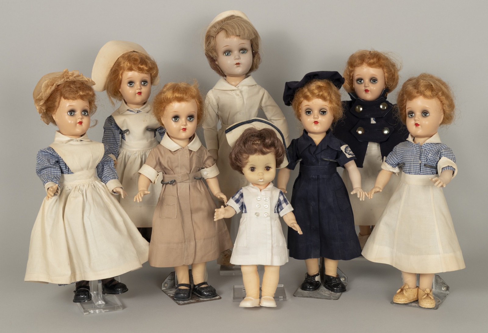 A group of eight dolls dressed in nurse uniforms.