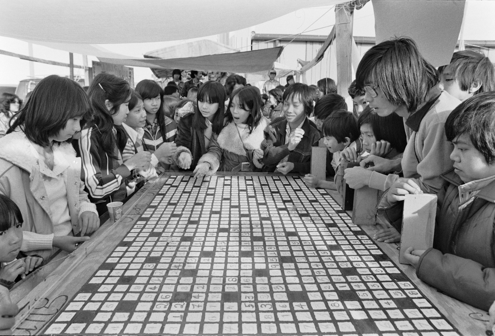 A vintage black and white photo shows a group of Vietnamese American teenagers at a Christmas Day youth fair playing a game.