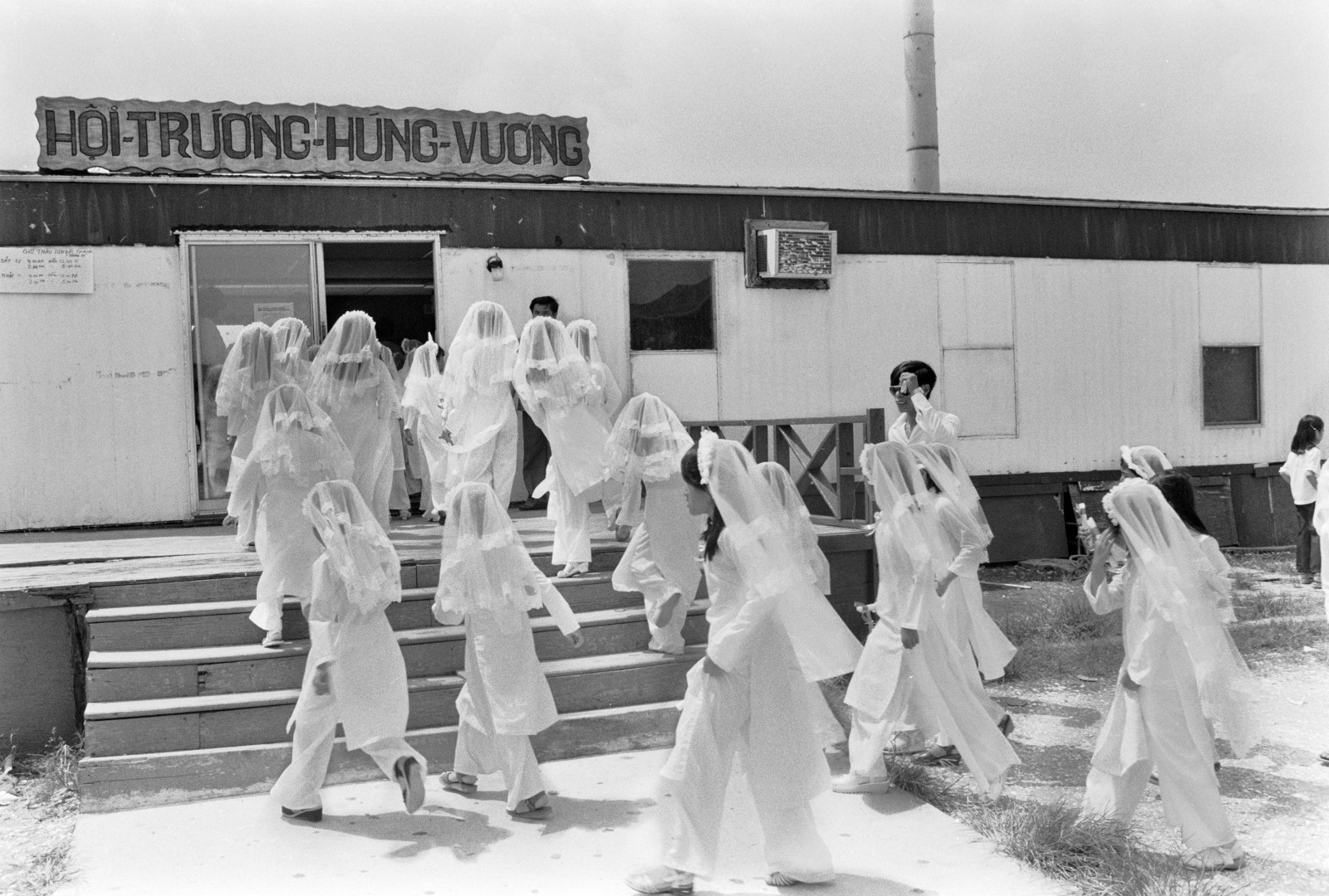 A vintage black and white photograph shows Vietnamese girls wearing veils between 1981–83.