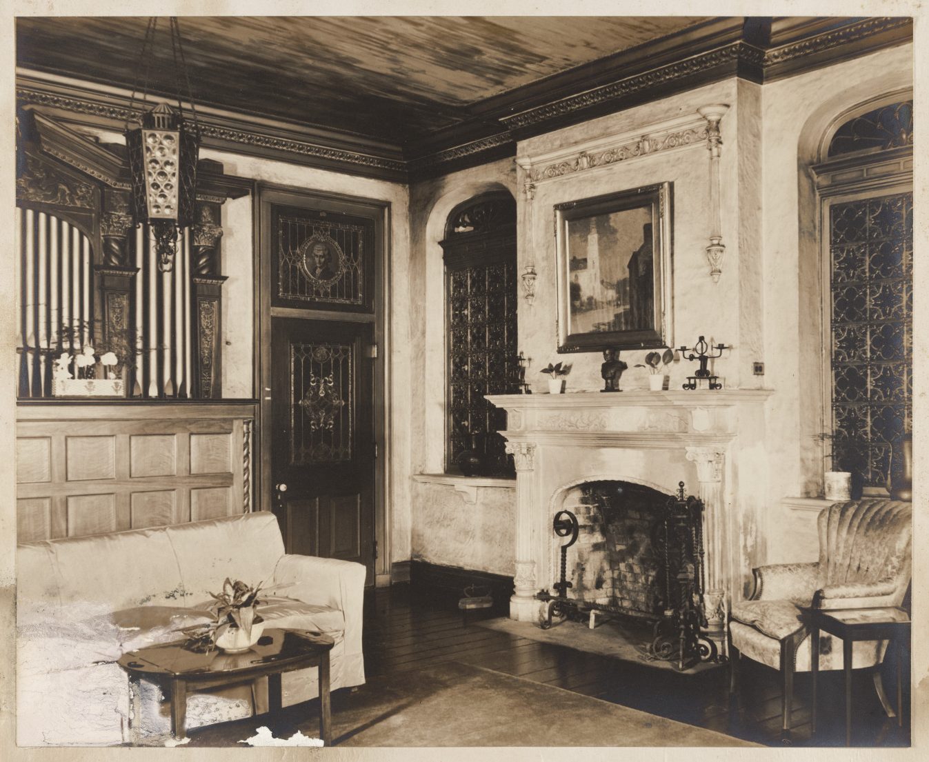 The photograph shows the music room of the Seignouret-Brulatour house at 520 Royal Street in the French Quarter of New Orleans. The Aeolian organ console is visible on the left side of the picture. Metal grilles over the openings to the spaces for the organ pipes are visible on the right side. A fireplace is visible on the right side. Furniture and other decorations of the room are visible.