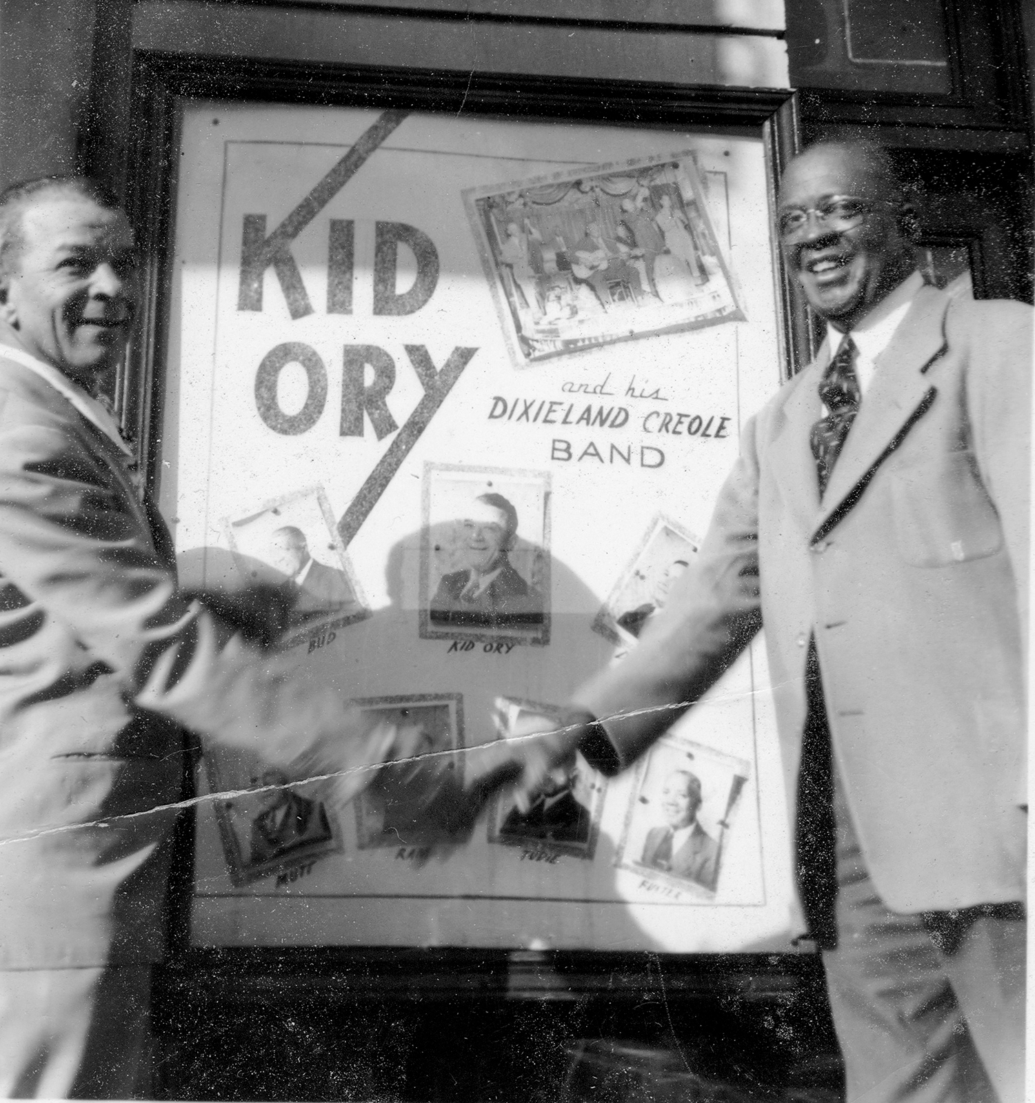 A black and white photo of Kid Ory and Bud Scott shaking hands in front of the Jade Palace 1946 in Los Angeles.