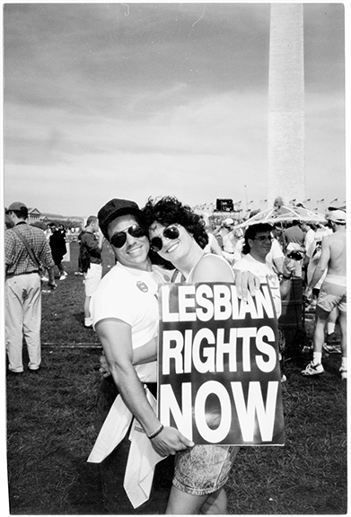 A black and white photo shows Larry and Susan Clade at the 1987 March on Washington. The Washington Monument can be seen in the background.