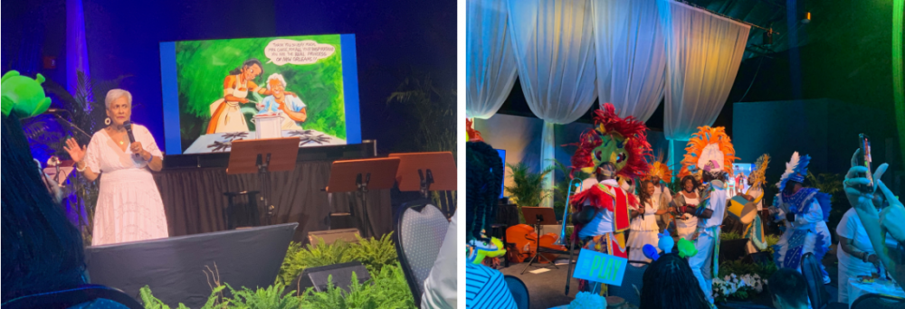 A woman in white speaks on stage with a colorful screen behind her. Next to her, a lively performance features people in vibrant costumes and headdresses. The stage is decorated with plants and drapery.
