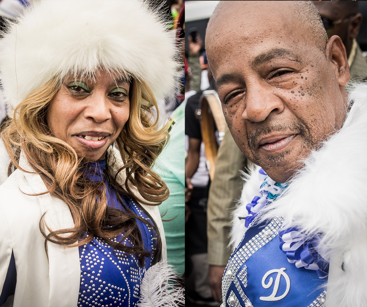 A woman and a man stand side by side wearing matching blue and white outfits. The woman has a white fur hat and a sparkly blue top, while the man wears a blue shirt with white feathers. Both are smiling slightly at the camera.