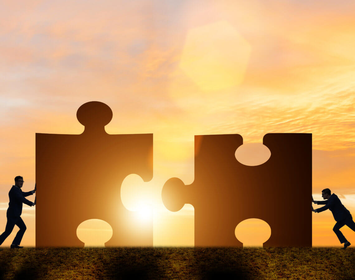 Two people pushing two large puzzle pieces together