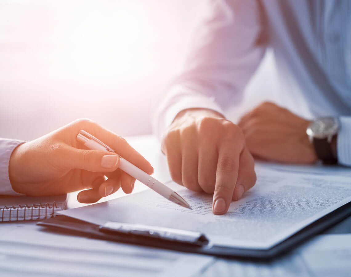 Pen in hand reviewing document with pointing figure