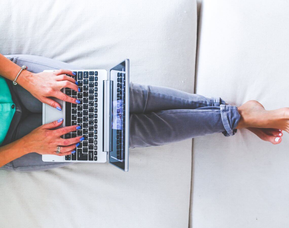 Woman lying and typing on laptop