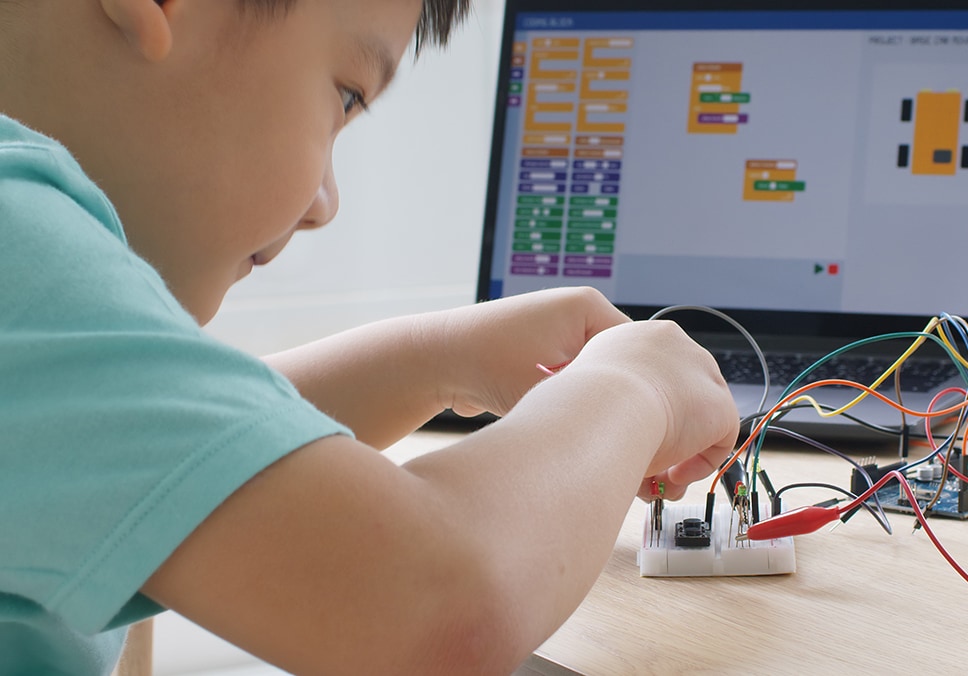 School student working with robotics at home with wires and an electronic map on a monitor