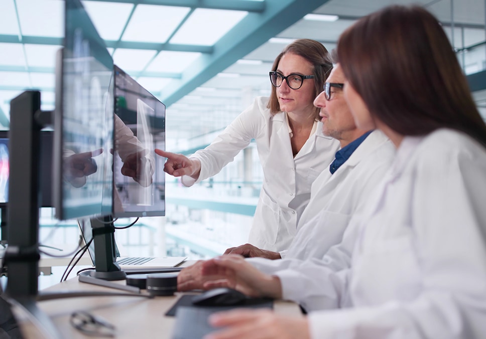 Medical researchers looking at data and scans on a monitor