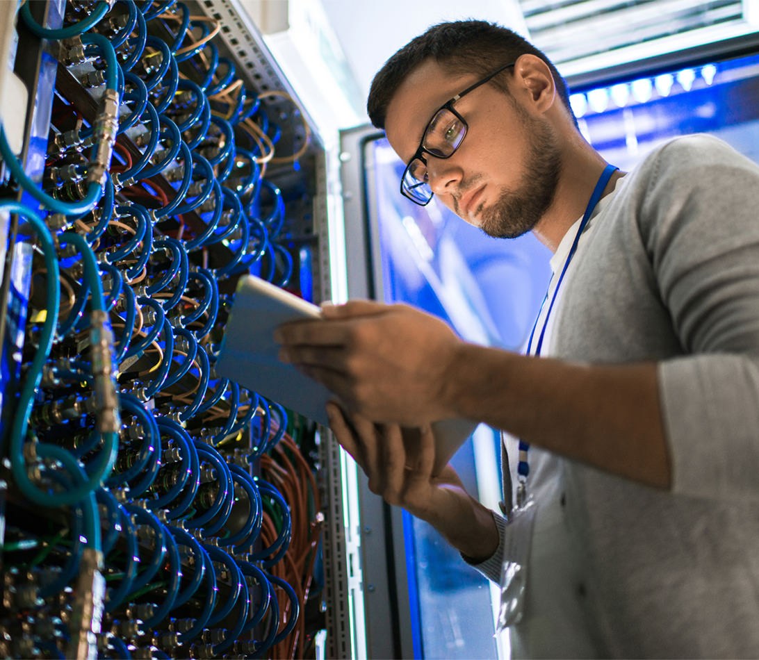 Technician working on tablet server rack fibre optic network monitoring