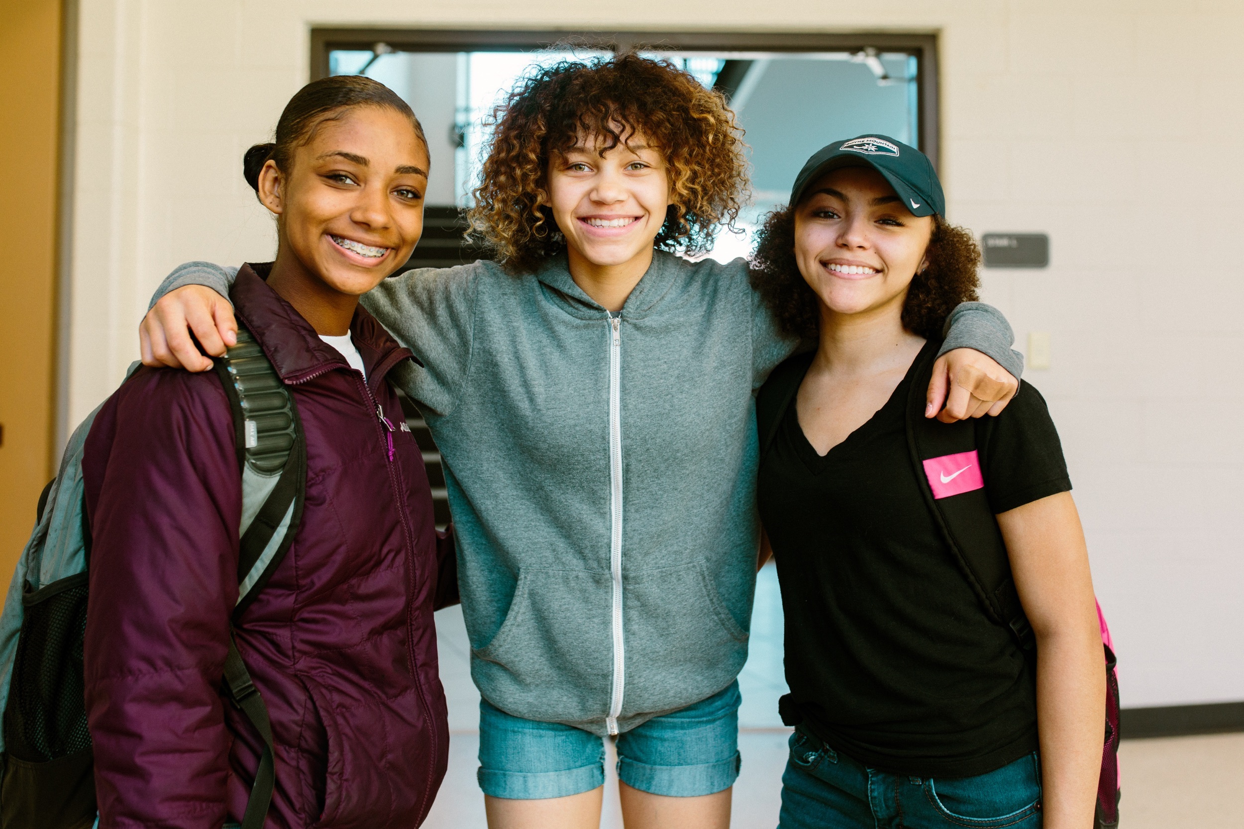Three students stand together smiling