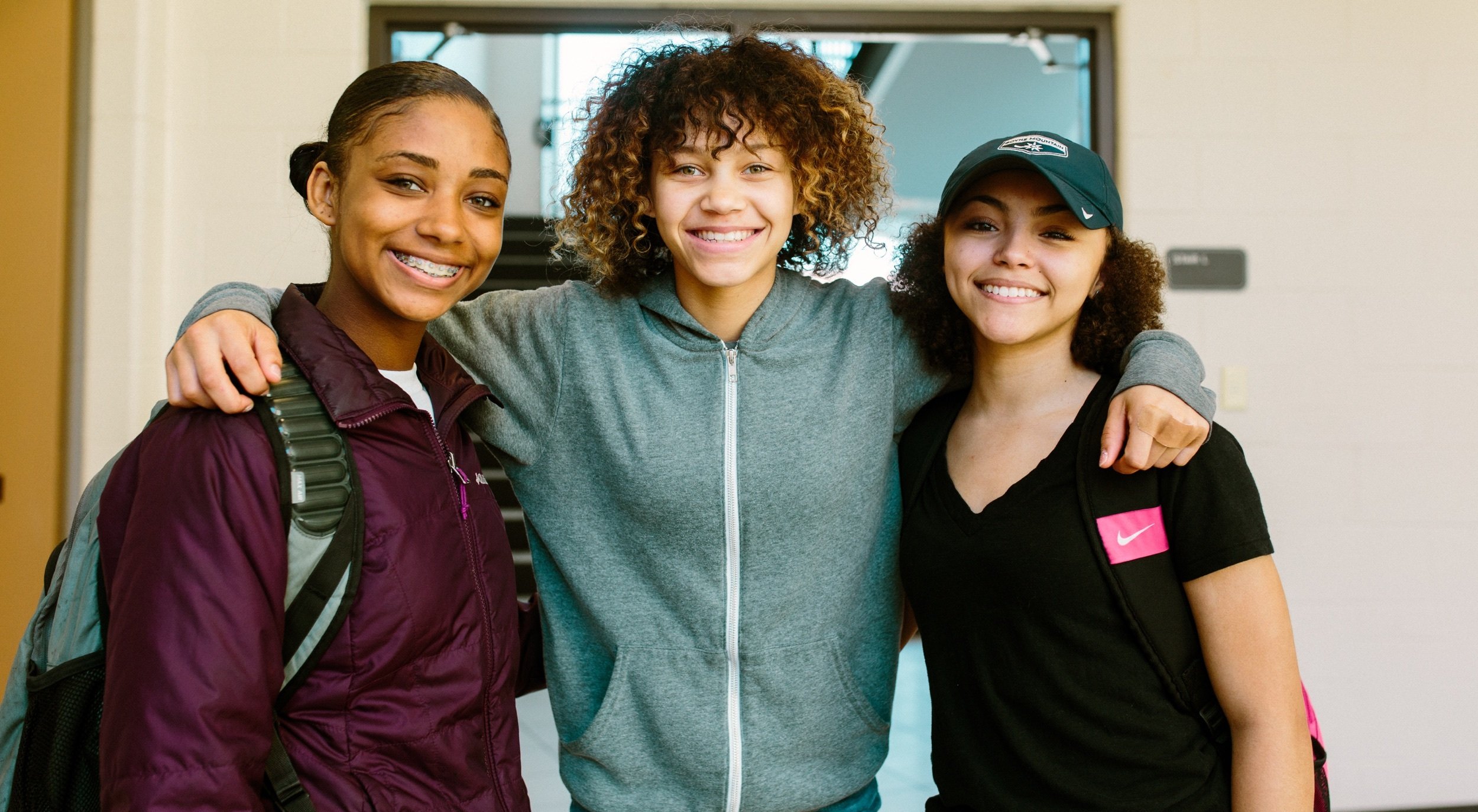 Three students stand together smiling