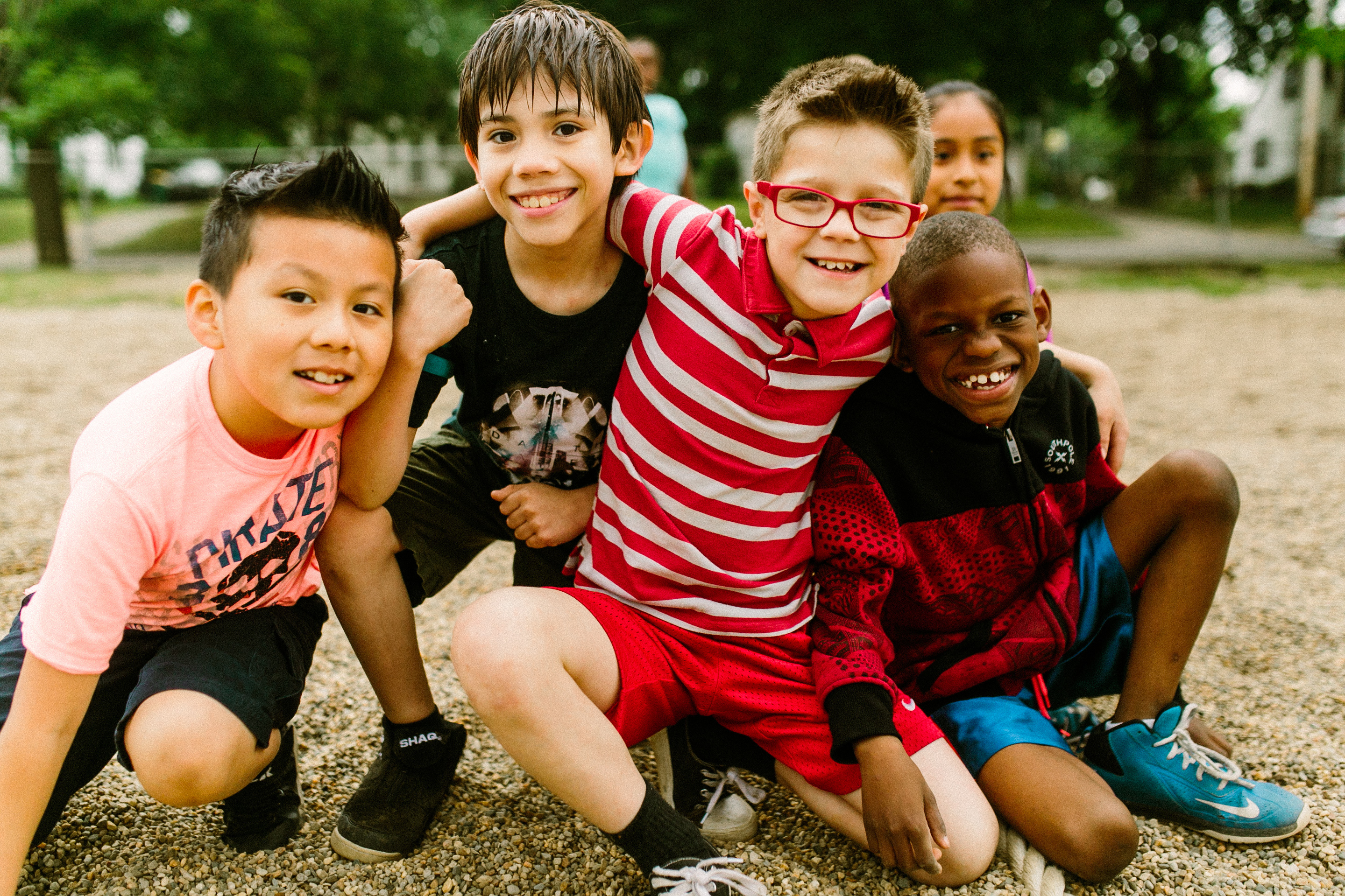 four young boys smiling crouched on ground
